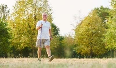älterer Herr beim Nordic Walking in einem Park