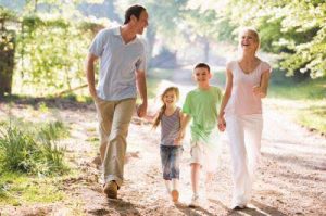 A young family walks through a summer park in a happy mood