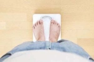 Primer plano de una persona más gorda en una balanza, el espectador tiene la vista de la persona que se pesa