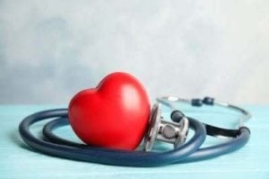 Primo piano di un cuore rosso e di uno stetoscopio su sfondo blu