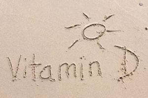 In den Sand geschriebenes Wort Vitamin D mit einer Sonne darüber