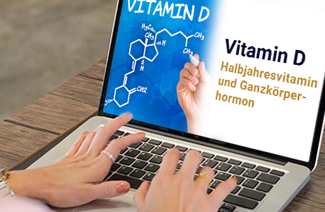 Frauenhände auf der Tastatur eines Laptops - auf dem Bildschirm ist eine Fachinformation zum Thema Vitamin D zu sehen