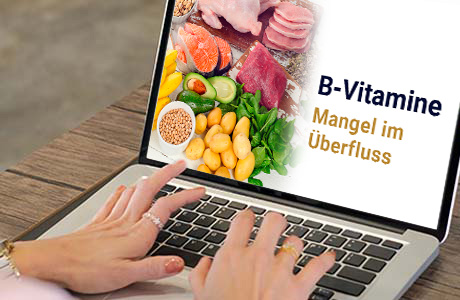Frauenhände auf der Tastatur eines Laptops - auf dem Bildschirm ist eine Fachinformation zum Thema B-Vitamine zu sehen