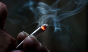 Primer plano de un cigarrillo que acaba de ser inhalado por un hombre
