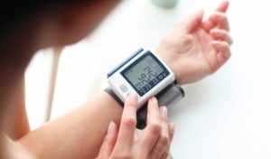 Ripresa di una donna che misura la sua pressione sanguigna. Il display mostra valori troppo alti