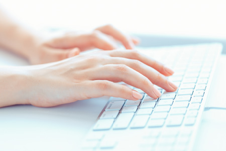 Nahaufnahme einer weiblichen Hand, die eine Eingabe auf einer Computer-Tastatur macht